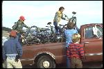 At the Azalea Hill drop off point for Repack. Bikes are unloaded from Vince Carlton’s brown Chevrolet pick-up truck. Left to right: Mark Green, standing, Charlie Kelly unloading his Excelsior, Alan Bonds helping Joe Breeze with Breezer #1, unidentified. Side view of truck with lots of bikes. October, 1977. 